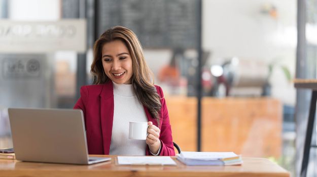 Attractive young asian woman using laptop computer while standing in a office...