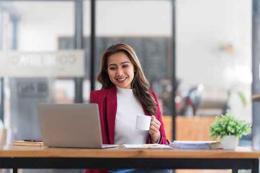 Attractive young asian woman using laptop computer while standing in a office...