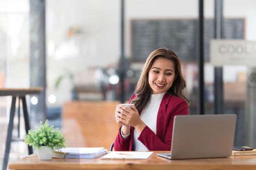 Attractive young asian woman using laptop computer while standing in a office...