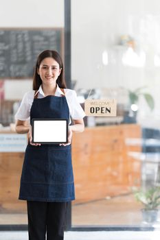 Young asia business owner woman with apron with open sign at cafe open again, showing blank white screen of tablet