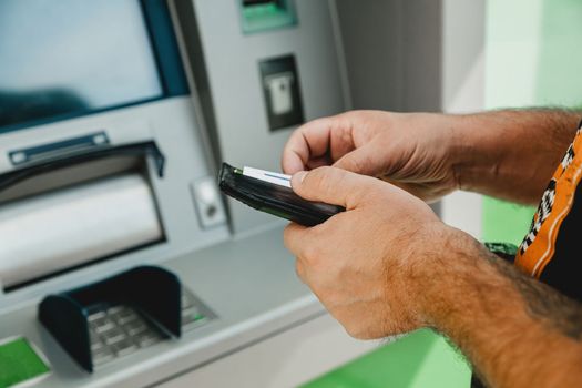 Man ATM card. ATM insert card. Man putting credit card in atm machine while holding wallet.