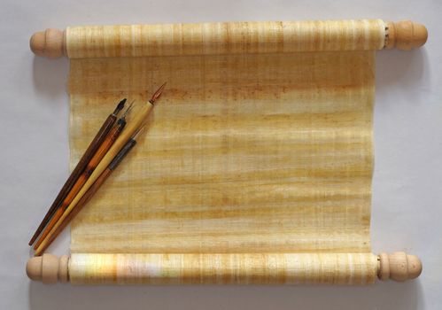 One papyrus scroll with four old fashioned nib pens with holder on top of it. Top table view. With space for your own text