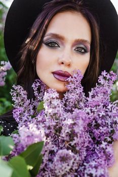 A fashionable girl with dark hair, a spring portrait in lilac tones in summer. Bright professional makeup