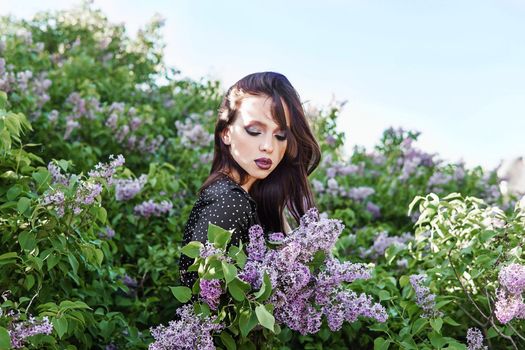 A fashionable girl with dark hair, a spring portrait in lilac tones in summer. Bright professional makeup