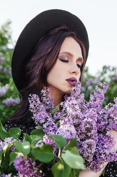 A fashionable girl with dark hair, a spring portrait in lilac tones in summer. Bright professional makeup