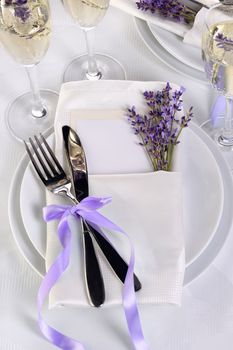 Lavender mood. Dining table in Provence style, with Lavender Champagne, folded napkin with cutlery, decorated with fresh lavender. Detail of the wedding dinner. Wedding theme ideas.