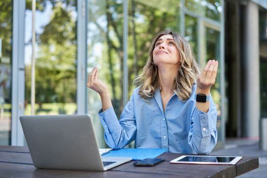 Frustrated businesswoman sitting on street with laptop and looking upset, disappointed. Concept of failure at work.