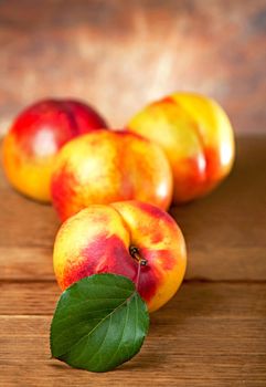 fresh nectarines with leaves on wooden background