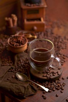 Tasty steaming espresso in cup with coffee beans. View from above. Dark background.