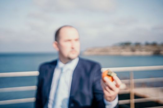 Male persimmon park. Hipster millennial man in a tie and jacket bites off a persimmon while sitting on a park bench in slow motion Young business people eat golden persimmons at lunchtime
