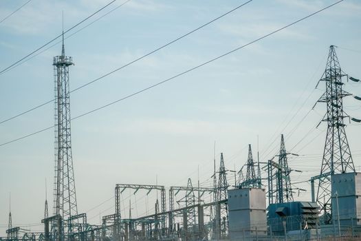 Silhouette High voltage electric tower on sunset time, distribution electric substation with power lines and transformers.