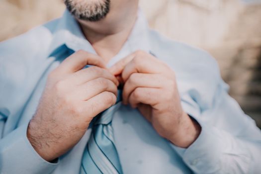 Close up of Man Adjusting Tie of Suit. Businessman in white shirt straightens his tie, close-up.