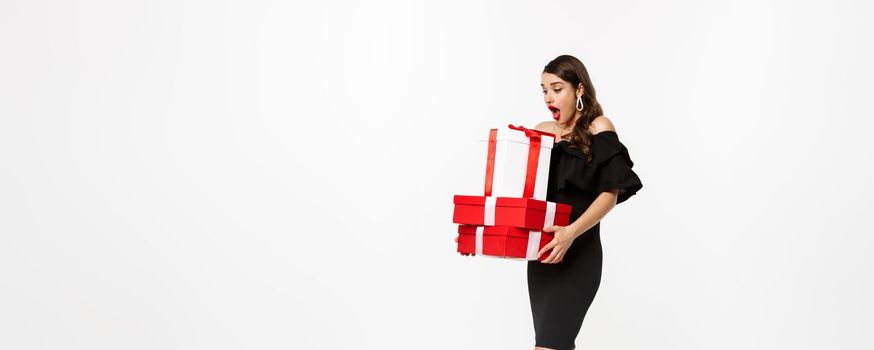 Merry christmas and new year holidays concept. Full length of attractive woman looking amazed at xmas gifts, receive presents, standing astonished over white background.