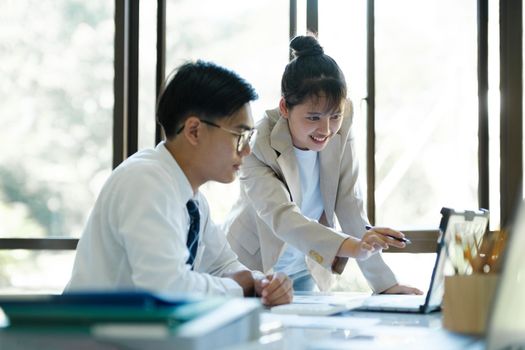 Businesspeople or colleagues are working together on investment project, discussing, sharing ideas, planning, and analyzing the business strategy and finance using laptop computer.