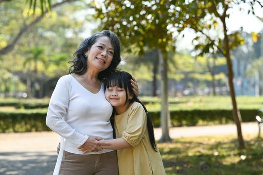 Affectionate grandmother hugging her adorable little grandchild, spending leisure weekend outdoor.