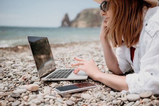 Woman sea laptop. Business woman in yellow hat working on laptop by sea. Close up on hands of pretty lady typing on computer outdoors summer day. Freelance, digital nomad, travel and holidays concept