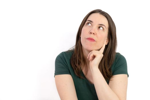 pensive young brunette woman gazing at the sky with her hand on her face white background