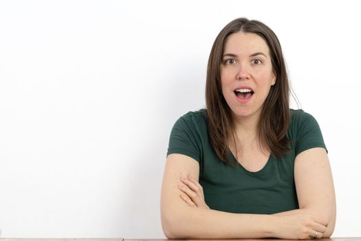 long-haired brunette woman with her mouth open surprised looking at the camera white background