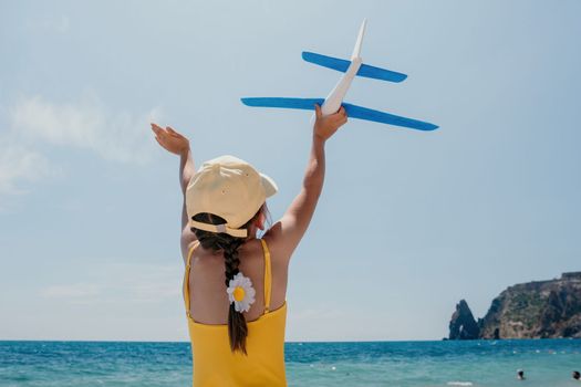 Kid playing with toy airplane. Children dream of travel by plane. Happy child girl has fun in summer vacation by sea and mountains. Outdoors activities at background of blue sky. Lifestyle moment