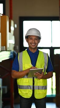 Image of man warehouse worker wearing hard hats and reflective jackets using digital tablet in retail warehouse.
