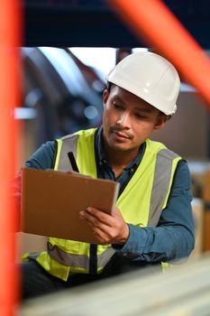 Storehouse worker checking stock and inventory on clipboard while sitting in retail warehouse. Business factory industry concept.