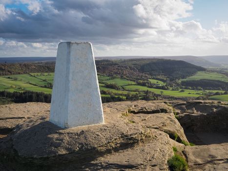 View from the summit of Roseberry Topping, Yorkshires Matterhorn, and white triangulation point, with Captain Cooks Monument on the distant hillside under moody sky, North York Moors National Park, UK