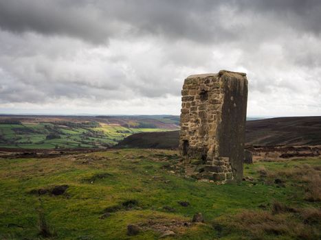 The remains of a winding house at Sheriffs Pit on the Rosedale Ironstone Railway, under dark moody sky, overlooking Rosedale valley, North York Moors National Park, UK