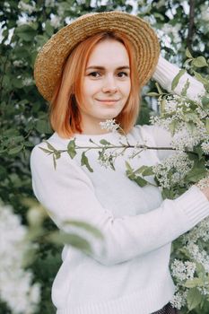 Portrait of a woman in a straw hat in a cherry blossom. Free outdoor recreation, spring blooming garden