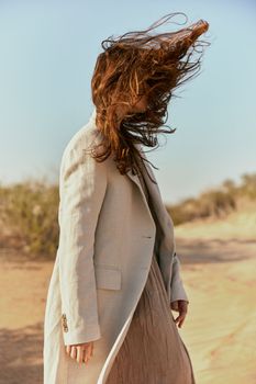 portrait of a woman in a light jacket with hair covering her face from the wind. High quality photo