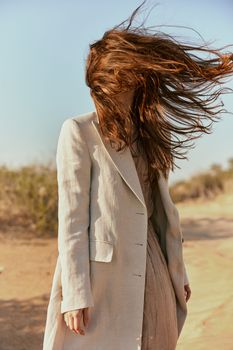 custom portrait of a woman in a light coat with red hair covering her face. High quality photo