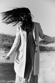 monochrome photo of a woman in a jacket against a clear sky on the coast. High quality photo