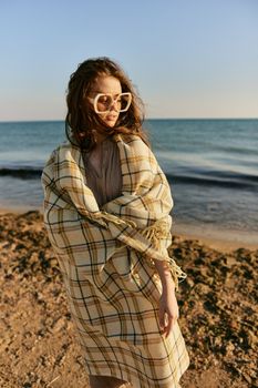 cute woman stands with a plaid during sunset on the beach. Rest, enjoyment. High quality photo