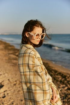 portrait of a beautiful woman with red hair blown by the wind on the sea coast wrapped in a plaid. High quality photo