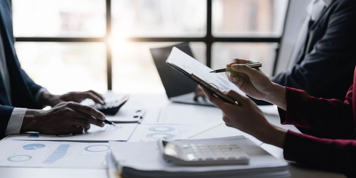 Group of confident business people point to graphs and charts to analyze market data, balance sheet, account, net profit to plan new sales strategies to increase production capacity