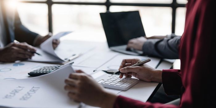 Group of confident business people point to graphs and charts to analyze market data, balance sheet, account, net profit to plan new sales strategies to increase production capacity