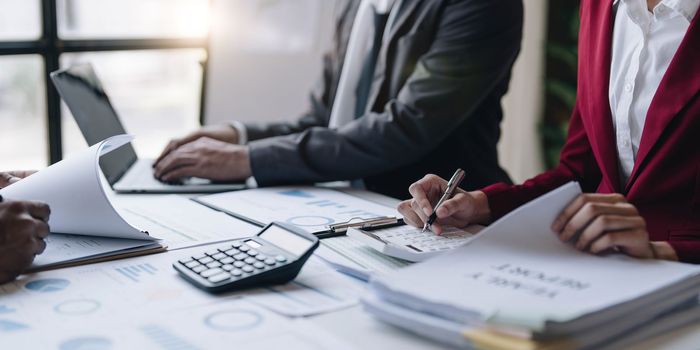 Group of confident business people point to graphs and charts to analyze market data, balance sheet, account, net profit to plan new sales strategies to increase production capacity