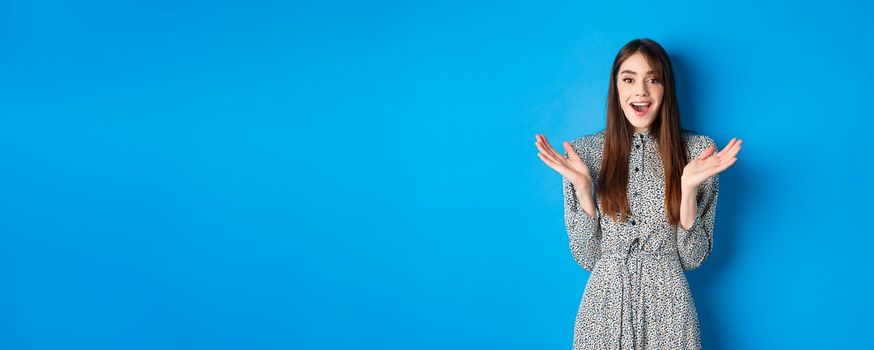 Excited beautiful woman clap hands and congratulate you, praising nice work, applause at camera and smiling, standing on blue background.