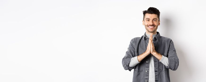 Thank you. Smiling friendly guy showing namaste gesture in gratitude, grateful for help, standing happy on white background.