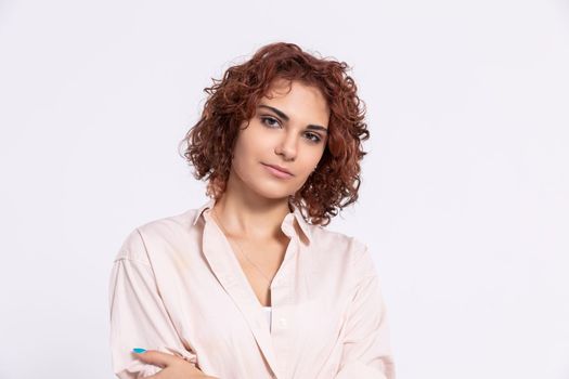 A gentle smile on her face. A European woman with chestnut-colored hair. A girl with fair skin and curly short hair looks straight ahead.