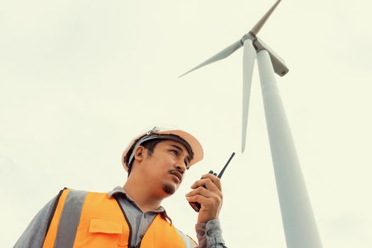 Engineer working on a wind farm atop a hill or mountain in the rural. Progressive ideal for the future production of renewable, sustainable energy. Energy generation from wind turbine.