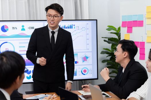 Confidence and asian businessman give presentation on financial analyzed by business intelligence in dashboard report to other people in board room meeting to promote harmony in workplace.