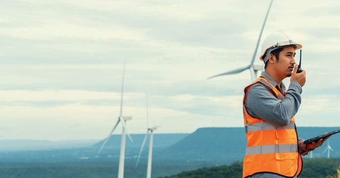 Engineer working on a wind farm atop a hill or mountain in the rural. Progressive ideal for the future production of renewable, sustainable energy. Energy generation from wind turbine.