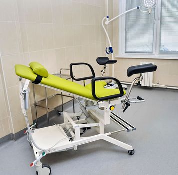 the gynecological chair in the doctor's examination room is green without people.