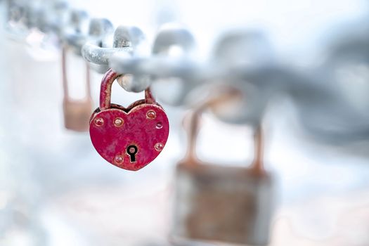 Red heart shaped lock hangs from chain, wedding custom, concept of love and health