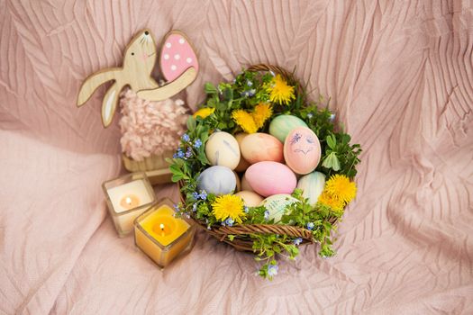 On a pastel bedspread is a basket of grass and various bright flowers, a rabbit. The basket contains Easter eggs painted with watercolors in beautiful pastel colors