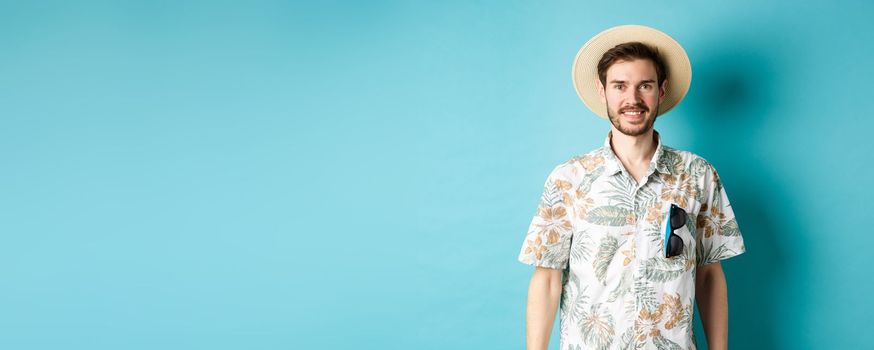 Happy and positive tourist in hawaiian shirt and straw hat, smiling at camera. Concept of tourism and summer holiday.