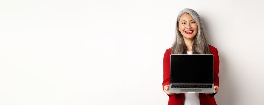 Business. Smiling asian businesswoman showing blank digital tablet screen, standing over white background.