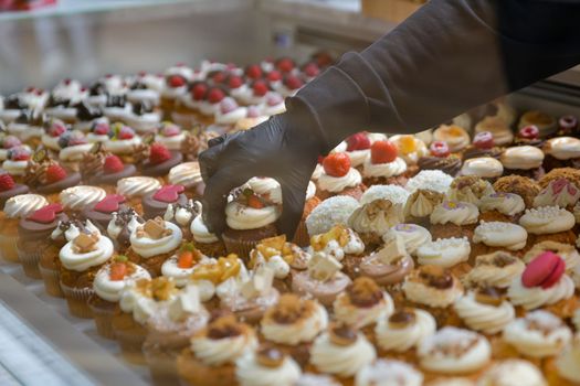Confectioner placing the cakes on a showcase for sale