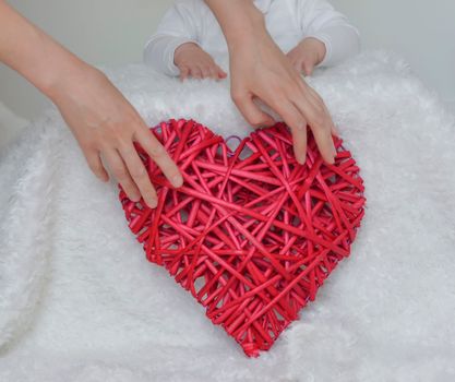 Red heart in the hands of mother with a child