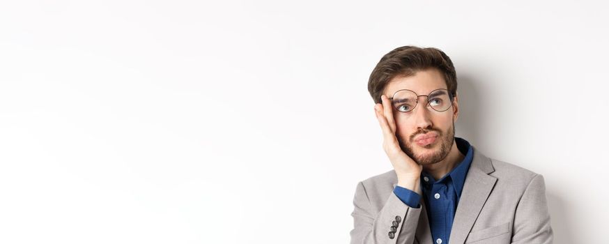 Close-up of shocked tired office worker takes-off glasses and stare at upper right corner with sad face, white background.